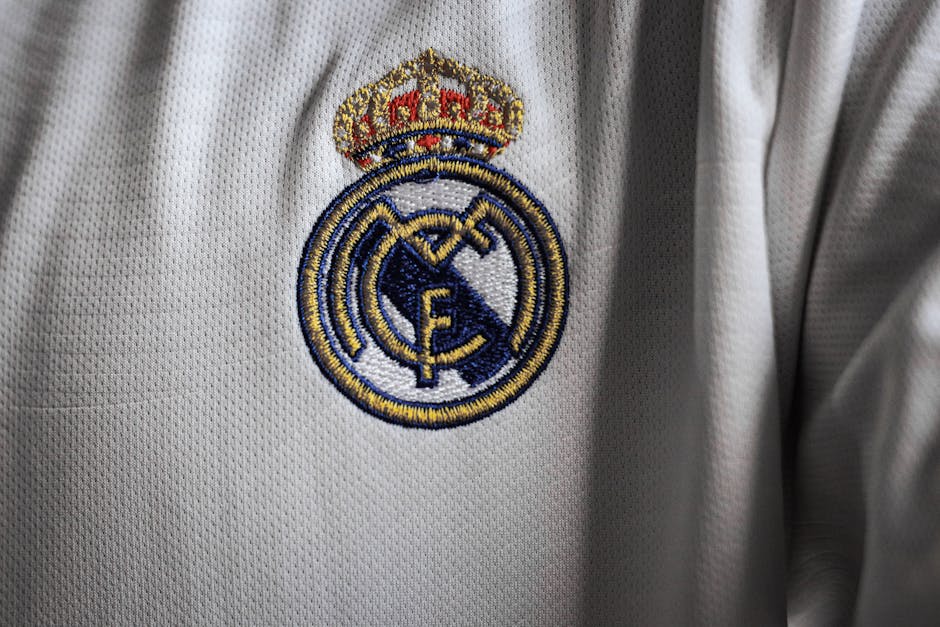 Detailed view of a famous embroidered logo on a white sports jersey fabric.