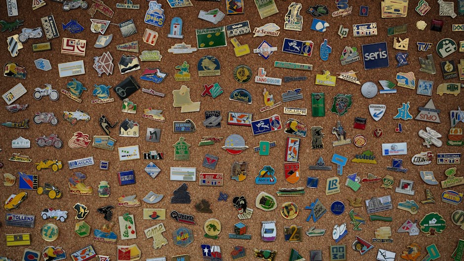 A diverse collection of vintage enamel pins displayed on a corkboard, showcasing unique designs and logos.