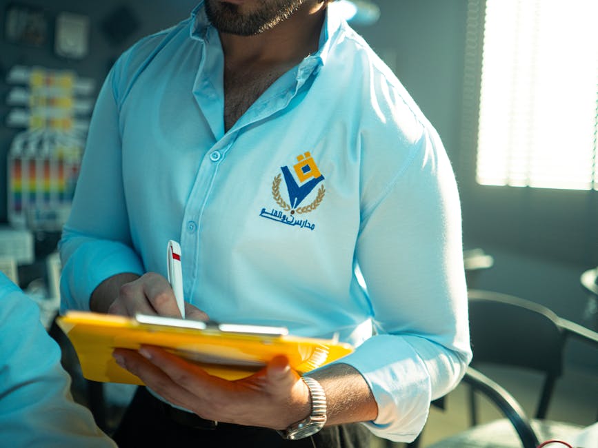 Man in professional attire holding a yellow notepad and pen in an office setting, depicted clearly with branding.